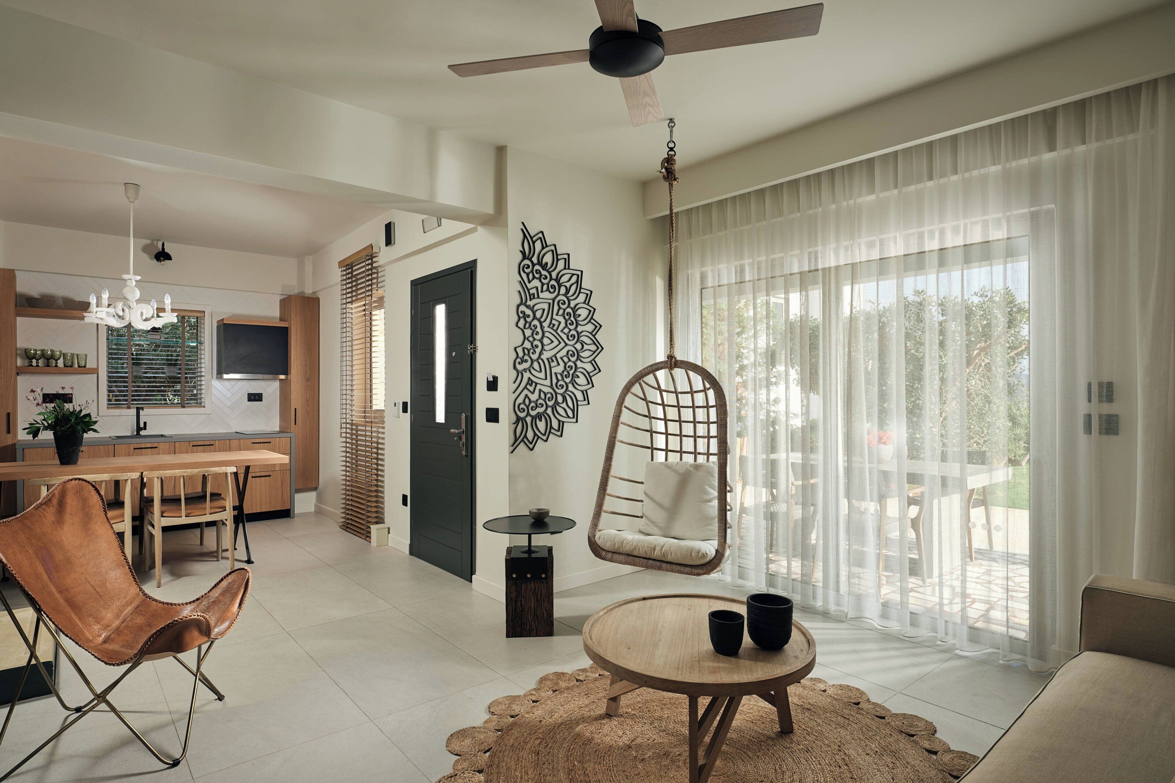 A modern living room with a hanging chair, a round coffee table, and a view of the outdoor patio.