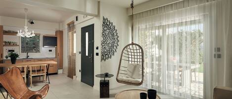 A modern living room with a hanging chair, a round coffee table, and a view of the outdoor patio.