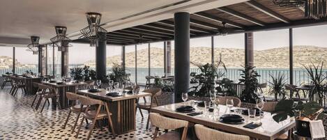 Un comedor interior con varias mesas, sillas y plantas en macetas.