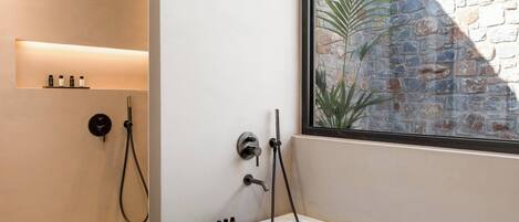 A modern bathroom with a shower, a bathtub, and a shelf with toiletries.