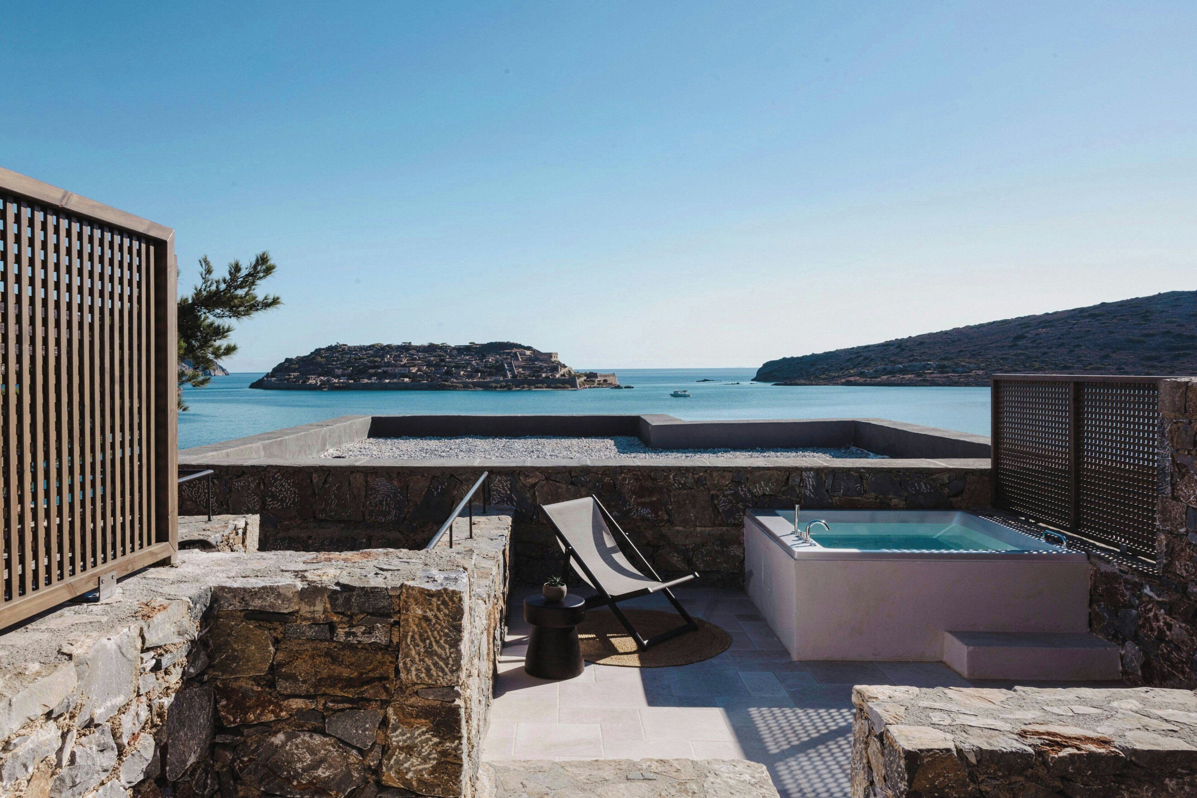 A rooftop terrace with a pool, lounge chairs, and a view of the sea.