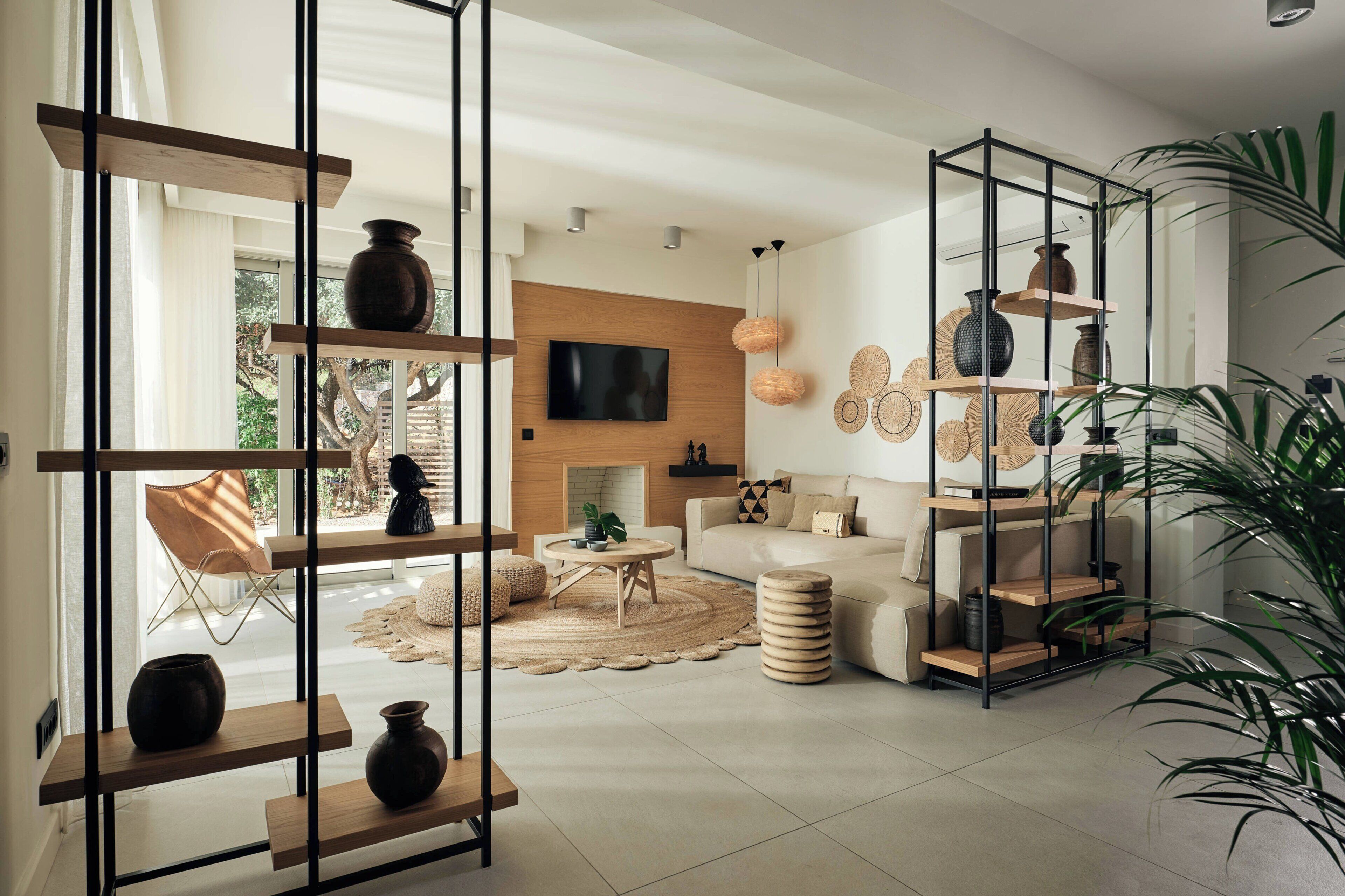 A modern living room with a fireplace, a television mounted on the wall, and a variety of decorative items on shelves.