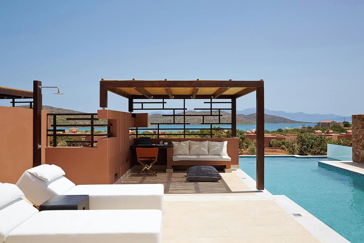 A rooftop terrace with a pool, seating area, and a view of the mountains.