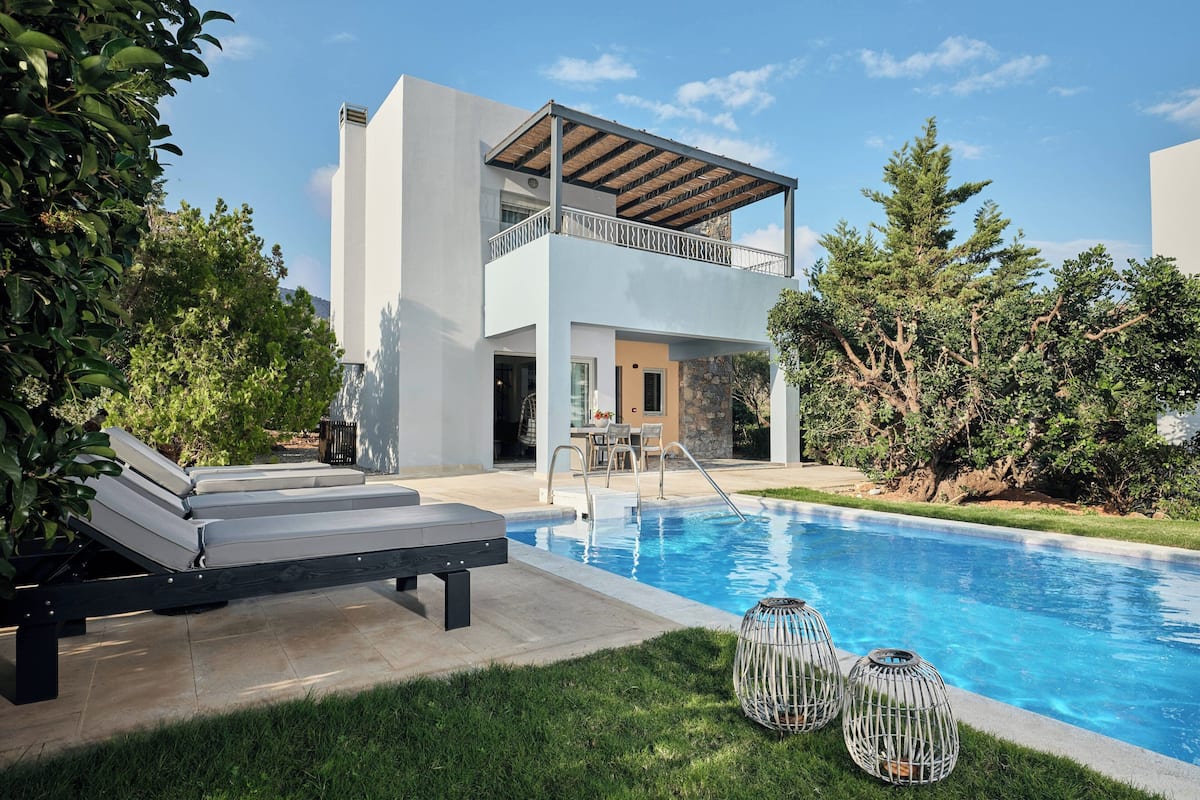 A modern two-story house with a swimming pool, outdoor seating, and a covered patio.