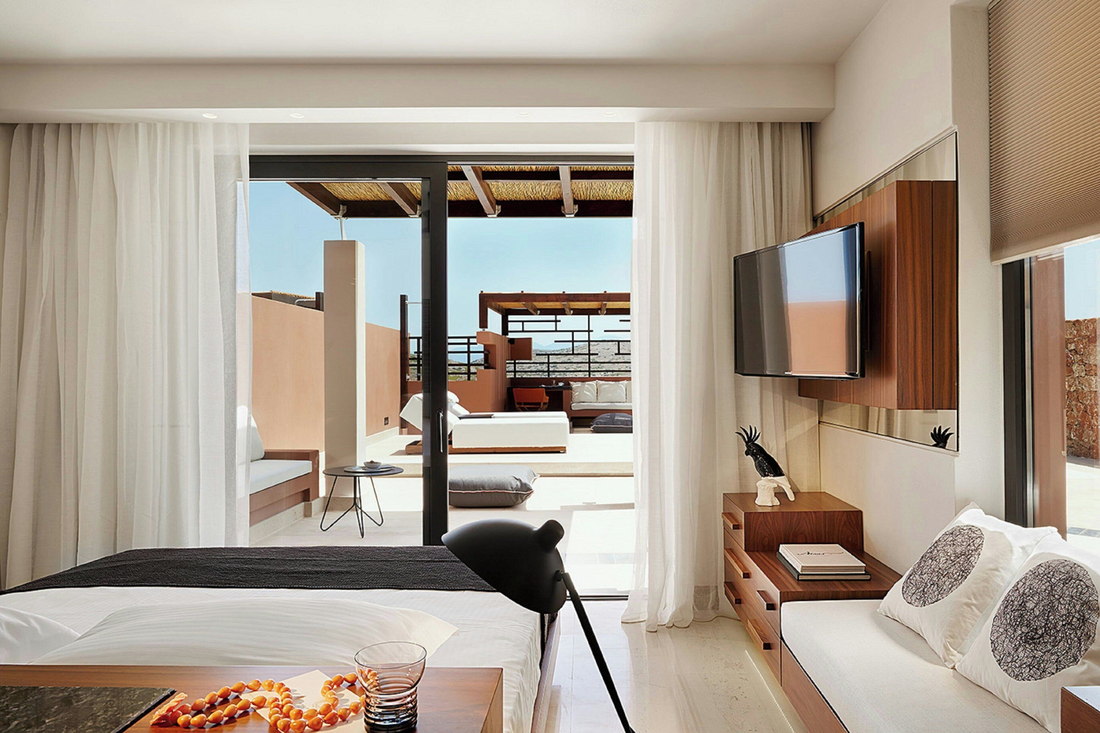 Une chambre d’hôtel moderne équipée d’un lit, d’un bureau, d’une télévision et offrant une vue sur l’espace extérieur.