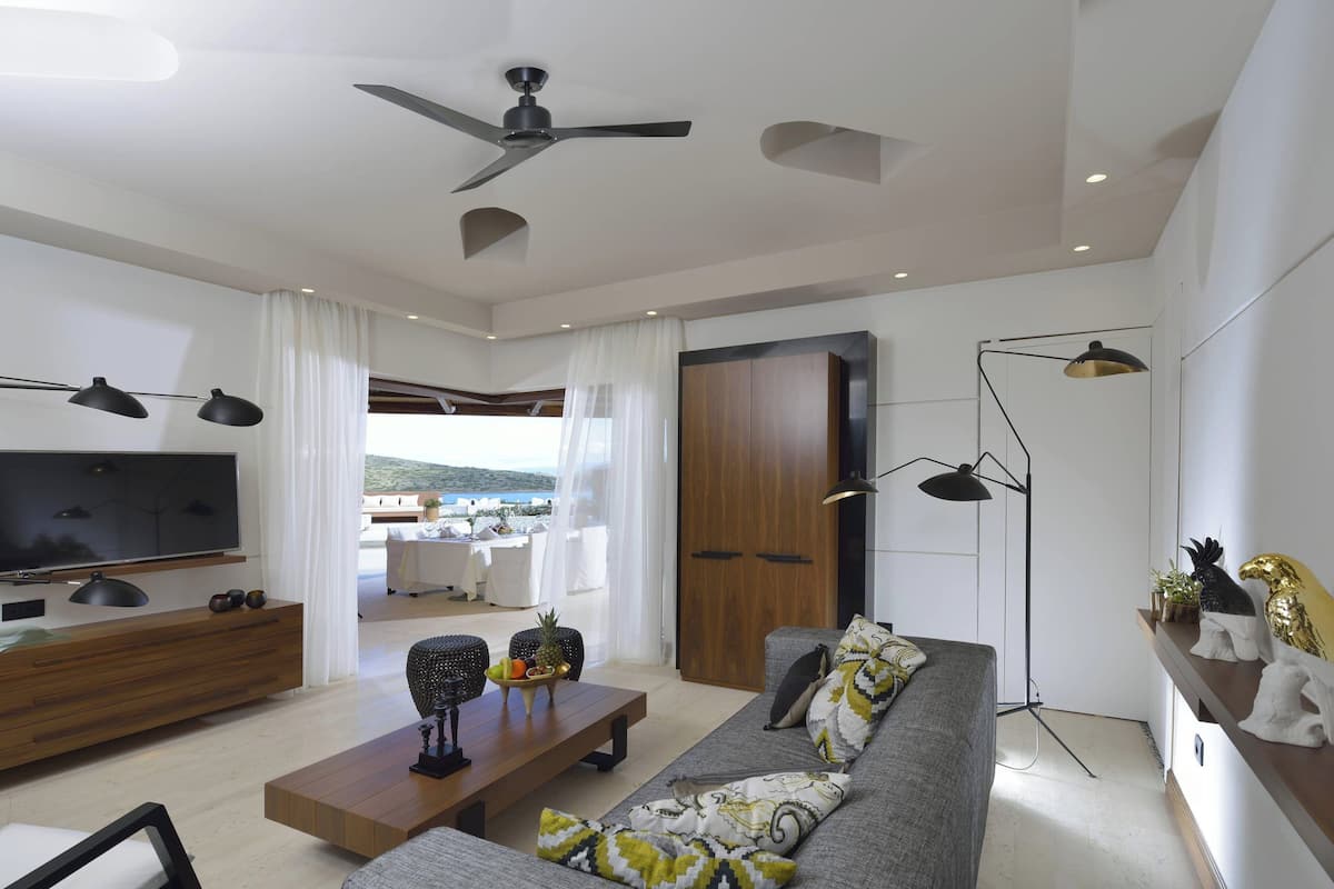 A modern living room with a flat-screen TV, sofa, coffee table, and a ceiling fan.