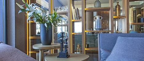 Ein modernes Interieur mit einer Couch, einem kleinen Tisch mit einer Vase und einem Bücherregal, gefüllt mit diversen Gegenständen.