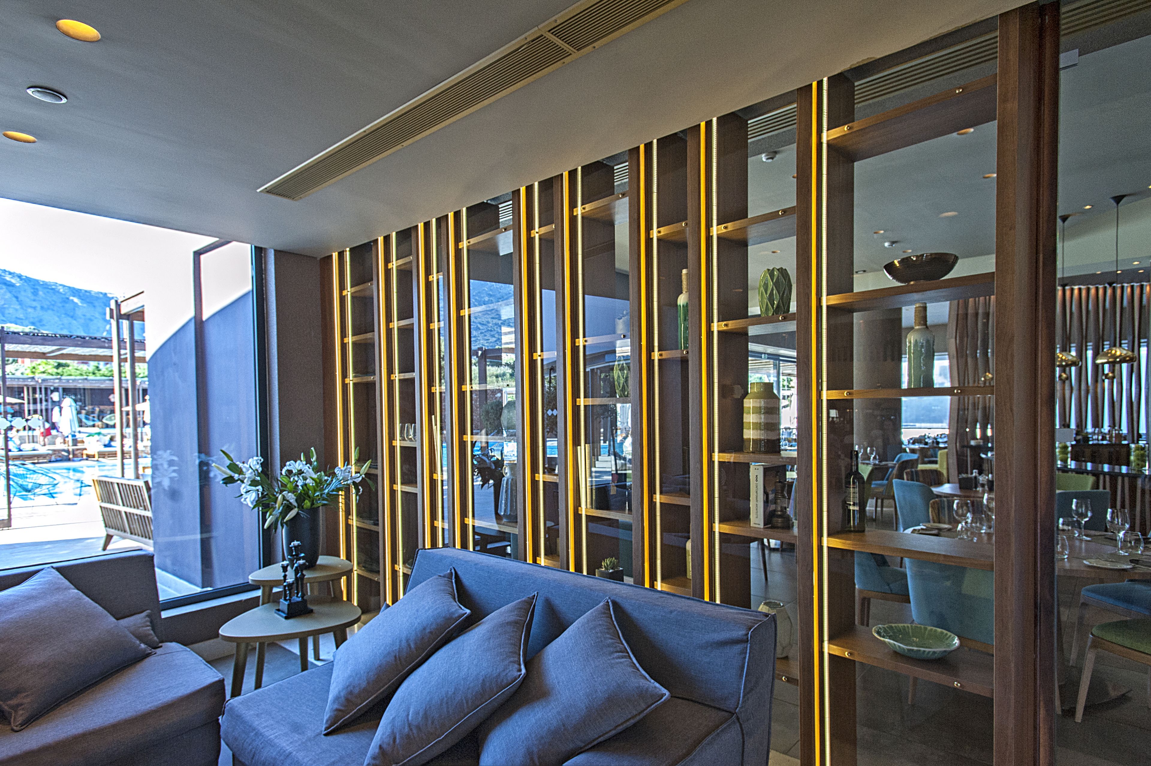 A modern interior with a sofa, a glass partition, and a dining area with chairs and tables.
