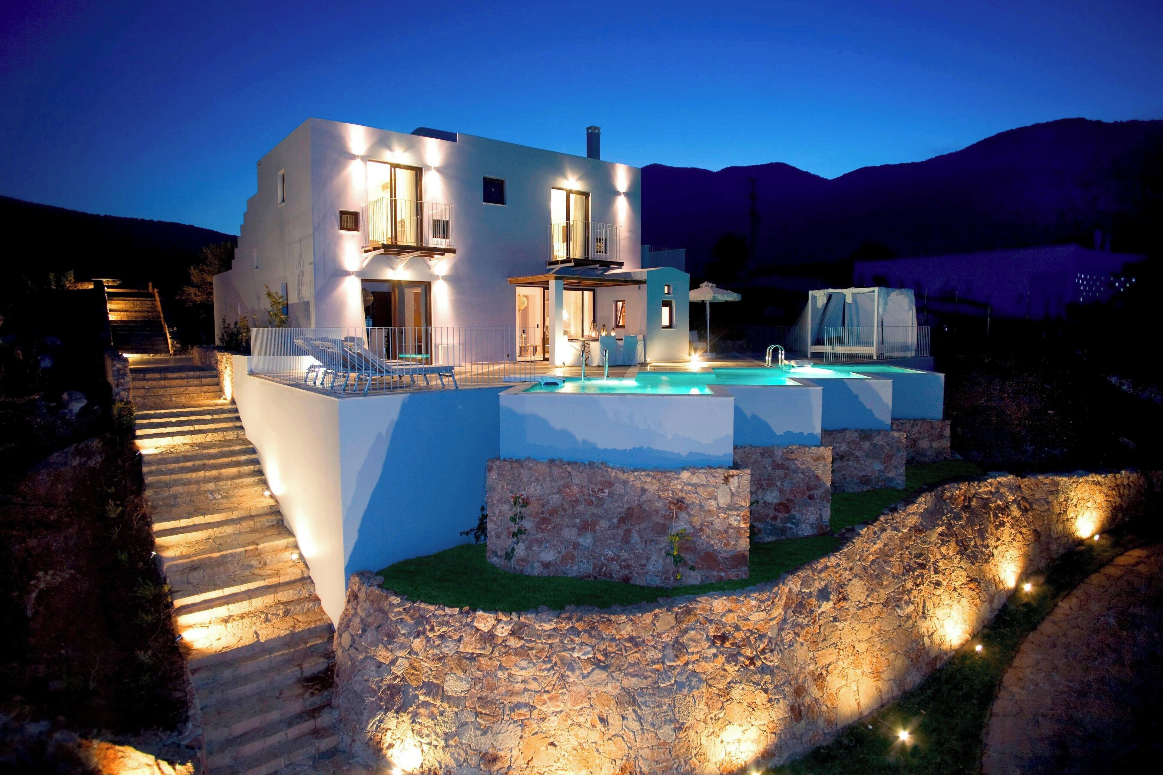 A modern house with a swimming pool, stone steps, and a view of the mountains.