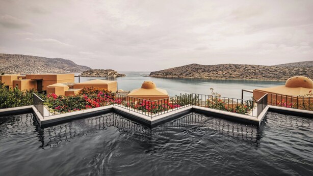 A pool area with a view of a body of water and hills in the background. - Domes of Elounda, Autograph Collection (Agios Nikolaos)