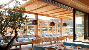 A restaurant with outdoor seating, wooden beams, and a view of a pool and mountains. - Domes of Elounda, Autograph Collection (Agios Nikolaos)