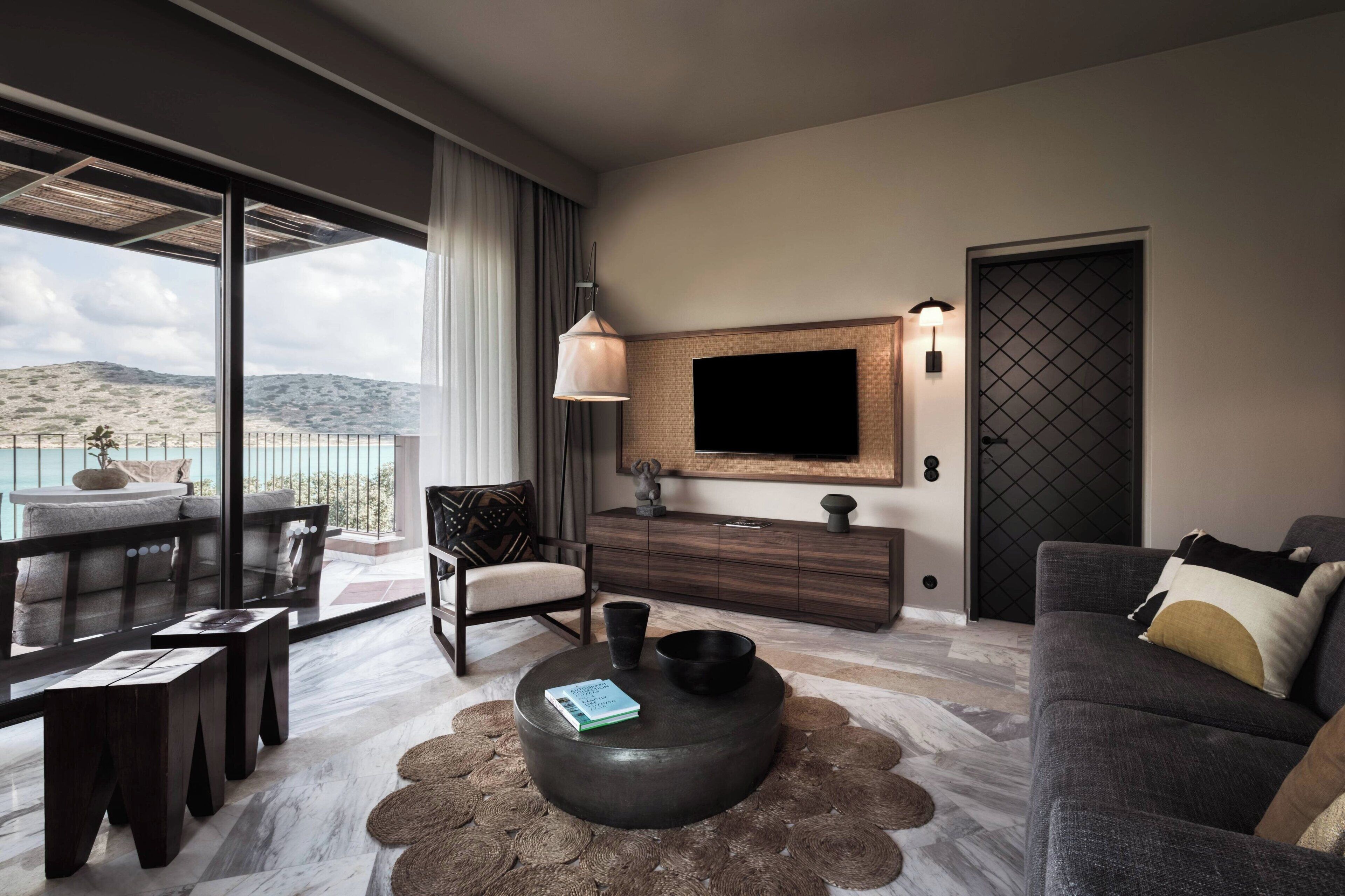 Una sala de estar moderna con un televisor grande, un sofá, una mesa de centro y vistas a la montaña.