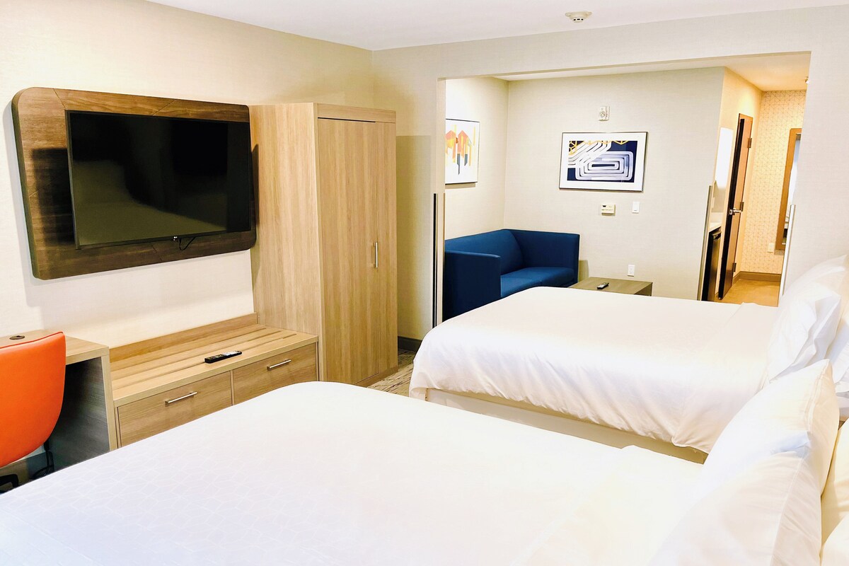 A hotel room with a bed, a desk, a chair, a TV, and a wardrobe.
