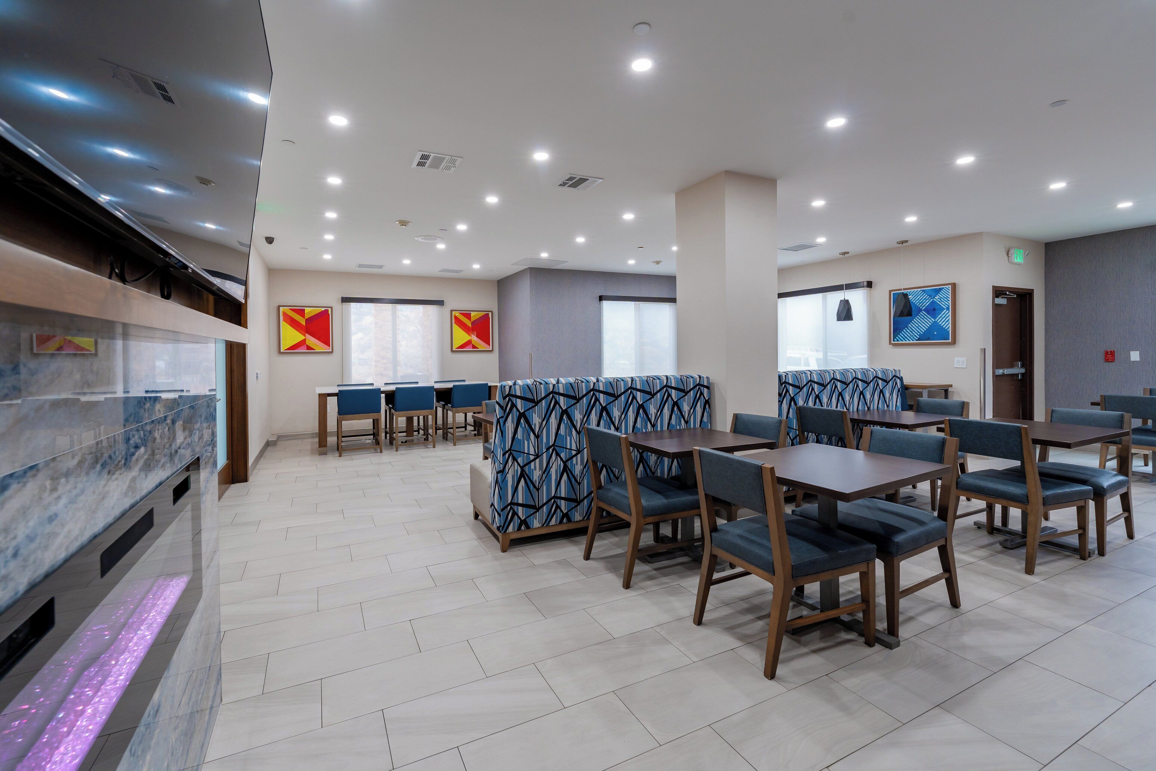 Un restaurante moderno con mostrador de mármol, cabinas con estampado azul y mesas y sillas de madera.