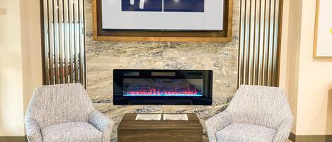 A Holiday Inn Express lobby with a fireplace, two armchairs, and a coffee table.