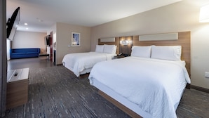A hotel room with two beds, a TV, a desk, and a blue sofa.