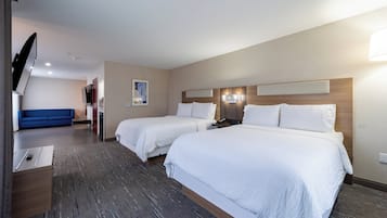 Une chambre d’hôtel avec deux lits, une télévision, un bureau et un canapé bleu.