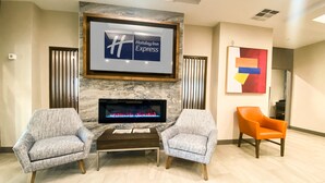 A lobby with a fireplace, two armchairs, a framed sign for Holiday Inn Express, and a colorful abstract painting. - Holiday Inn Express & Suites Frazier Park by IHG (Lebec)