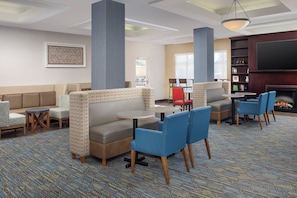 A hotel lobby with seating areas, a fireplace, and a television.