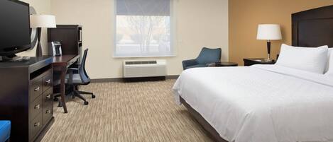 A hotel room with a bed, desk, chair, television, and two lamps.
