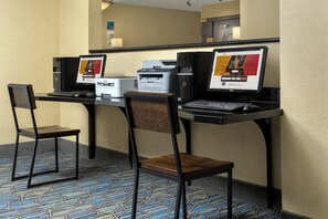 Ein Hotelzimmer mit Schreibtisch, zwei Stühlen, einem Desktop-Computer, einem Drucker und einem Laptop.
