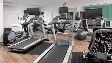 Un gimnasio con cintas de correr, elípticas y pelotas de ejercicio.