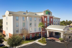A multi-story hotel with a prominent Express & Suites sign, a covered entrance, and a parking area.