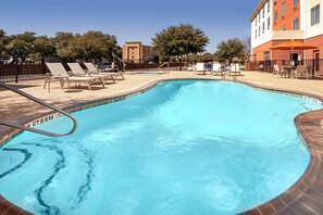 A swimming pool with lounge chairs and a building in the background. - Holiday Inn Express Hotel & Suites Uvalde by IHG (Uvalde)