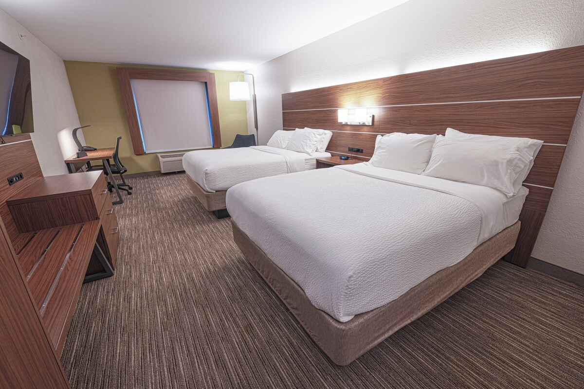 A hotel room with two beds, a desk, and a chair.