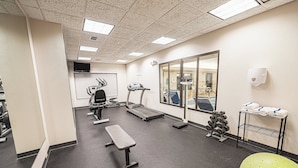 A gym with treadmills, a bench, a green exercise ball, and a rack of dumbbells. - Holiday Inn Express Hotel & Suites East Lansing by IHG (East Lansing)