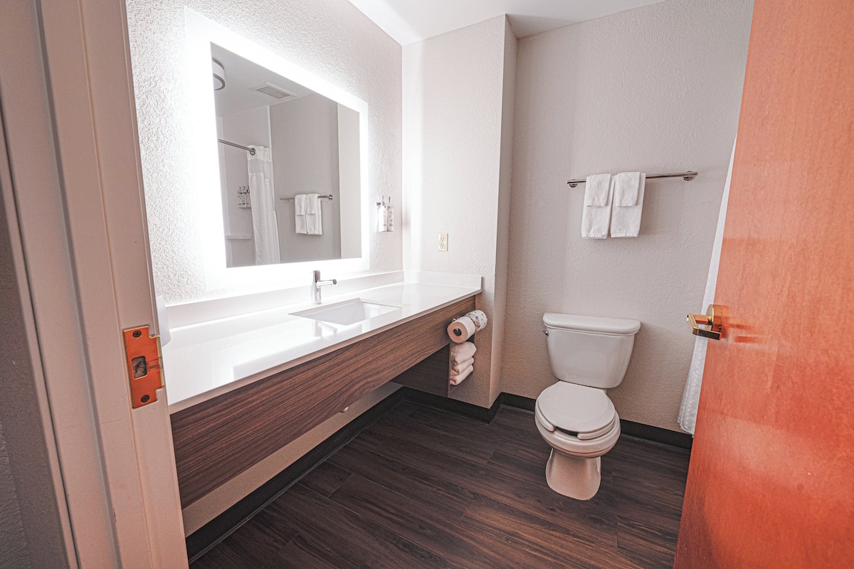 A modern bathroom with a large mirror, white sink, and toilet.