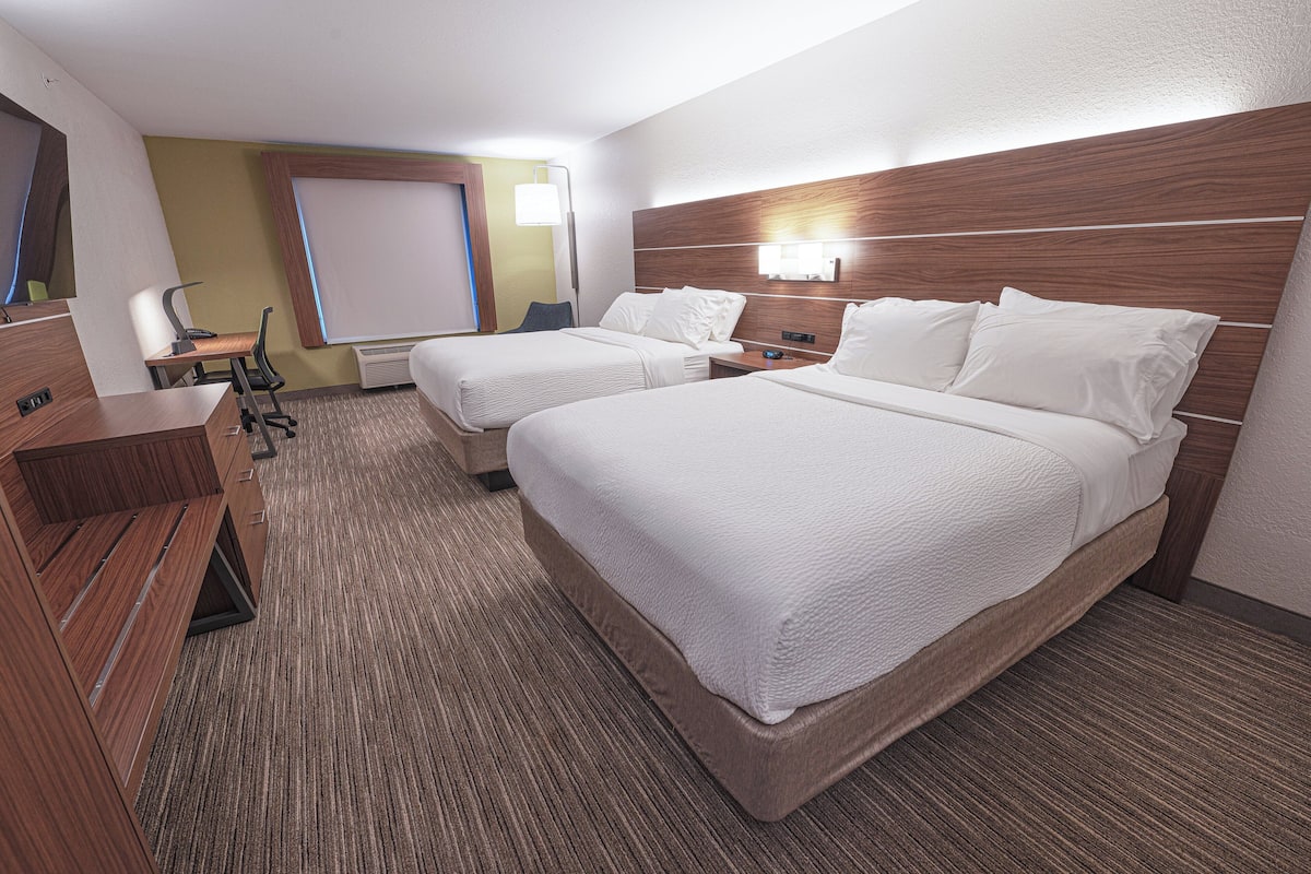 A hotel room with two beds, a desk, and a chair.