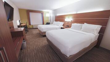 Habitación de hotel con dos camas, un escritorio, una silla, un televisor y una ventana con persianas.