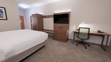 Une chambre d’hôtel comprenant un lit, un bureau avec une chaise, une télévision et une lampe.