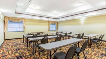A conference room with tables and chairs, a patterned carpet, and a ceiling with recessed lighting.