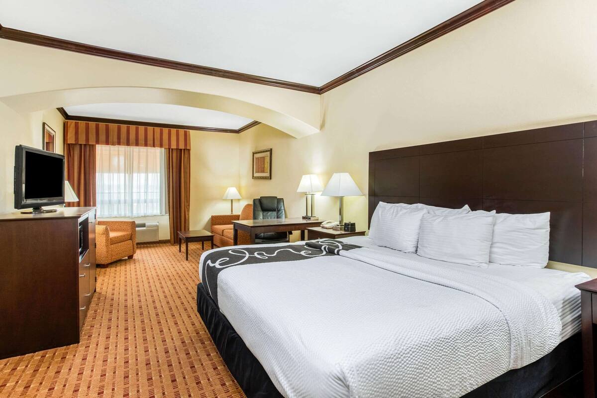 Ein Hotelzimmer mit einem großen Bett, einem Schreibtisch, einem Fernseher und einem Sessel.