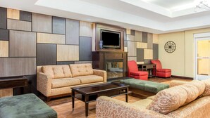 Un salon moderne comprenant un canapé, des fauteuils, une table basse et un téléviseur à écran plat fixé au-dessus d’une cheminée.