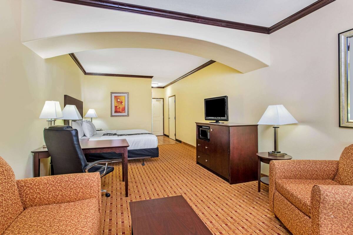 Ein Hotelzimmer mit Bett, Schreibtisch, Stuhl, Fernseher und zwei Lampen.