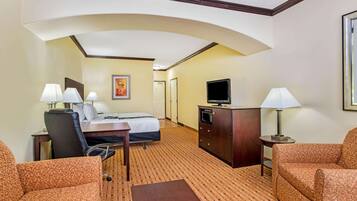 A hotel room with a bed, desk, chair, television, and two lamps.