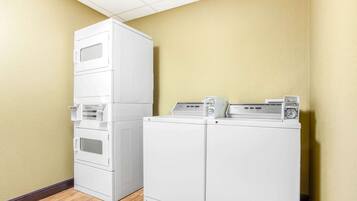 A laundry room with stacked washers and dryers, wooden flooring, and yellow walls.