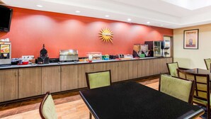 Une cuisine d’hôtel dotée d’un long comptoir, de divers appareils et d’un coin repas avec des chaises et une table.