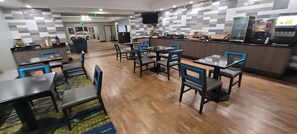 Un restaurant moderne avec un plancher en bois, des chaises bleues et des tables.