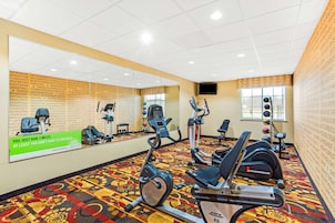 A gym with various exercise equipment, a patterned carpet, and a motivational poster.