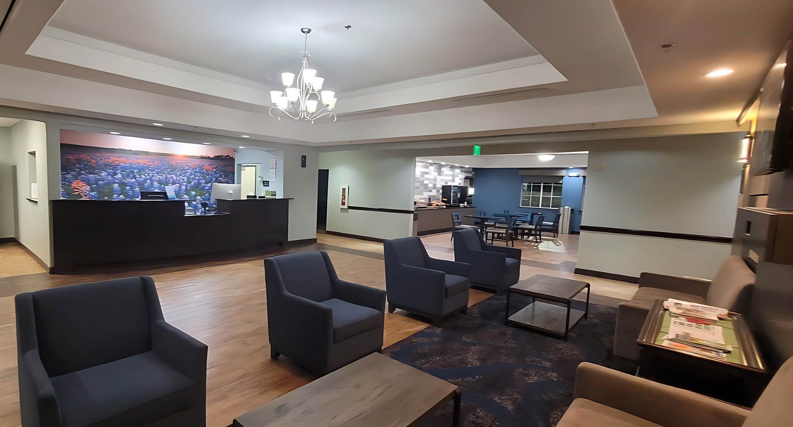 A hotel lobby with a reception desk, seating area, and a dining section.