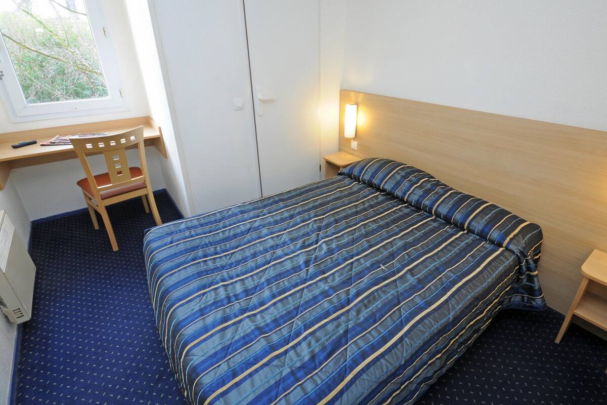 Un dormitorio con cama, escritorio y silla.