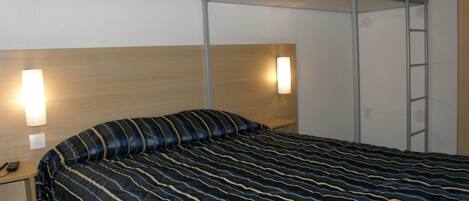 A bunk bed with a striped bedspread, a bedside table with a phone, and a wall-mounted light fixture.