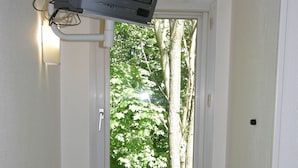 A small room with a desk, a chair, a window with a view of trees, and a television mounted on the wall. - Mister Bed Lomme (Lille)