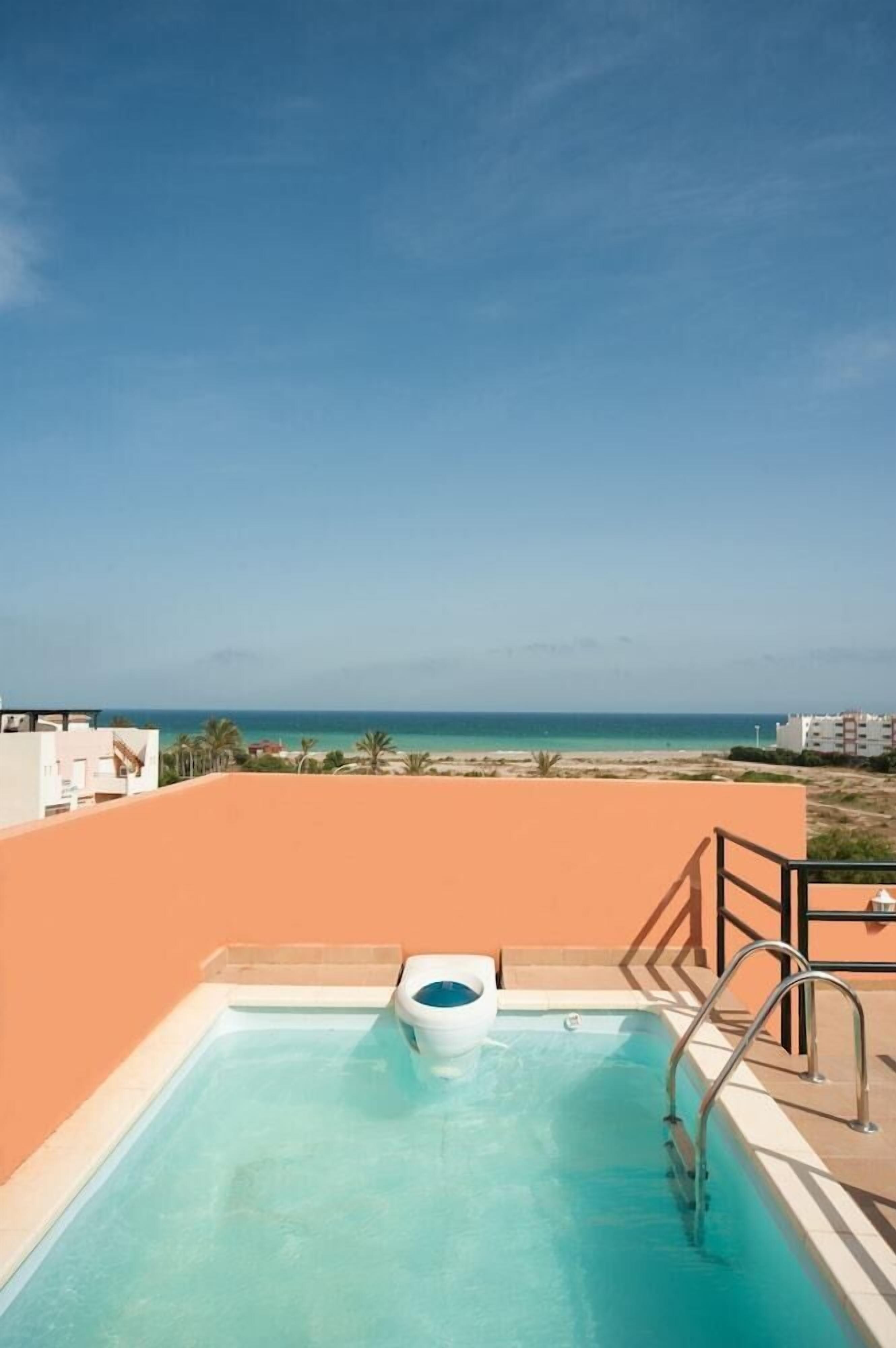 A rooftop pool with a view of the beach and ocean.
