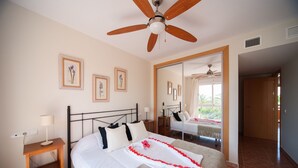 A neatly arranged bedroom with a bed, bedside table, and a ceiling fan. - Apartamentos Paraiso Playa (Vera)
