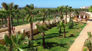 A coastal resort with palm trees, a paved walkway, and a beach in the background. - Apartamentos Playamarina (Ayamonte)